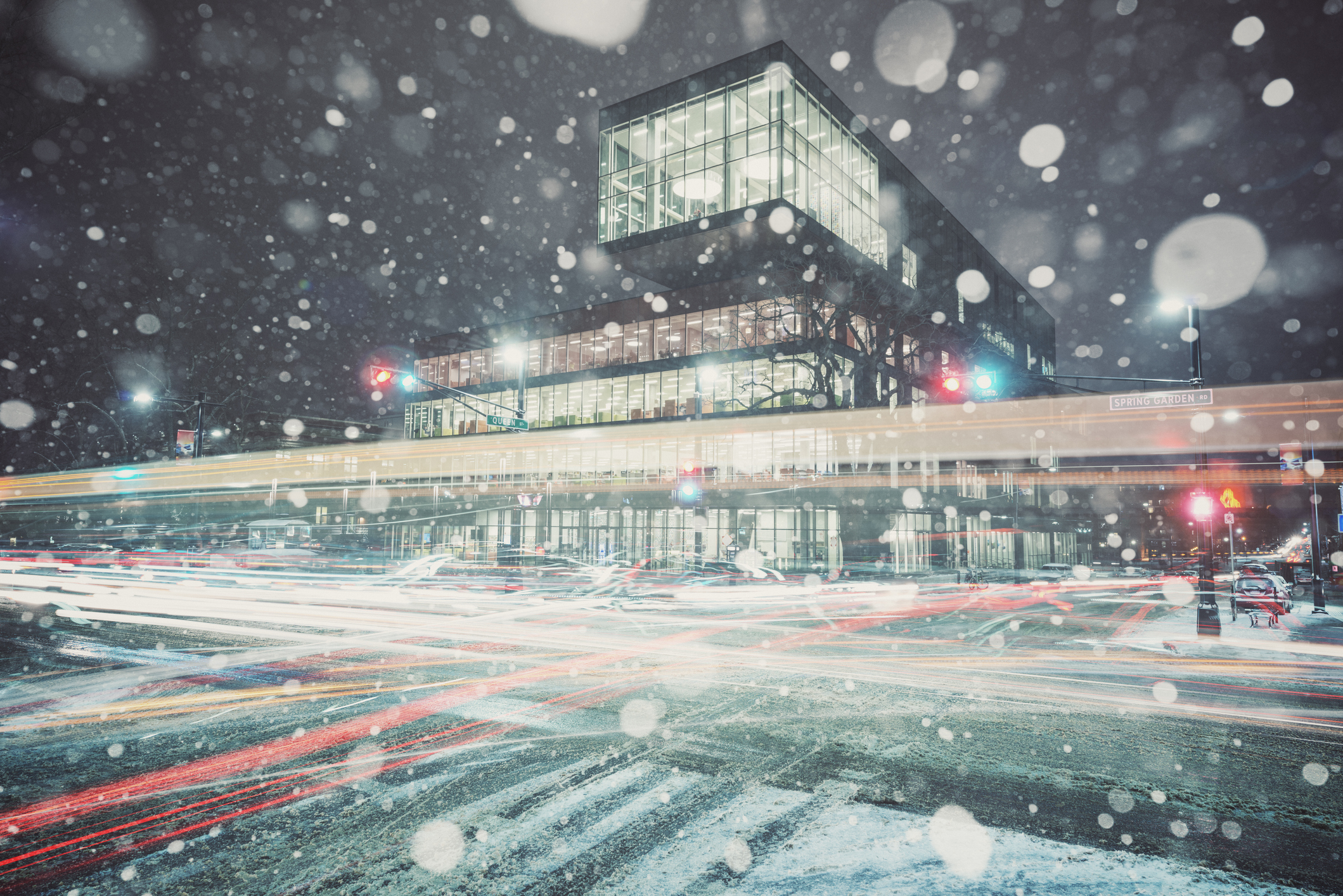 A blur of motion and falling snow at the intersection of Spring Garden and Queen streets in front of the newly completed Halifax Central Public Library.  Long exposure.