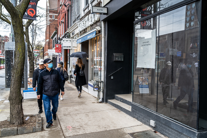Toronto, Canada - May 02, 2020: Locals on the streets of Downtown Toronto on a rainy day during coronavirus pandemic in Ontario, Canada.